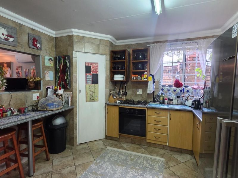 A functional kitchen featuring laminate cabinetry, a built-in oven with gas hob, tiled splashbacks, and a convenient breakfast bar area.