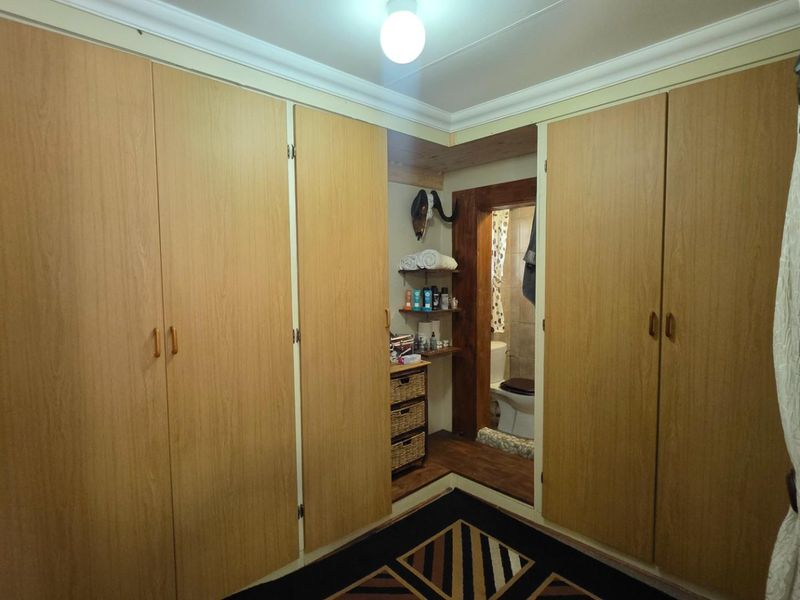 Bedroom featuring extensive built-in wooden cabinetry and direct access to an adjoining en-suite bathroom.