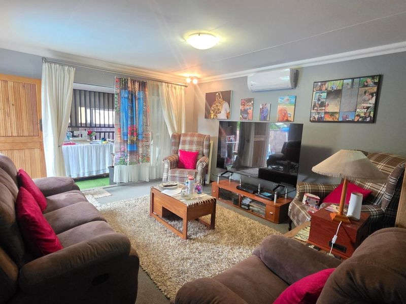 A comfortable living room featuring an air conditioning unit, neutral wall finishes, and direct access to an outdoor patio area through sliding glass doors.