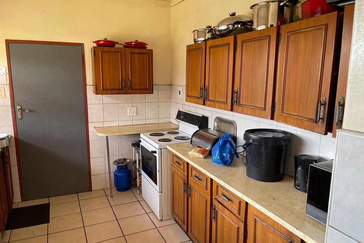 A dated kitchen featuring wooden cabinetry, tiled splashbacks, and a freestanding stove, offering potential for modernization and renovation.