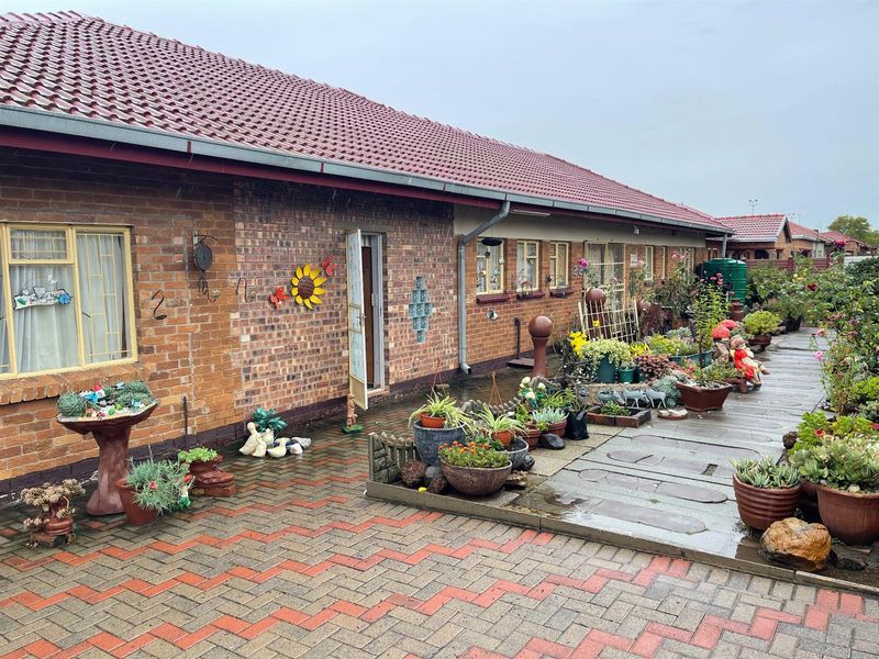 A view of the rear exterior of the house featuring a paved patio area, brick facade, and tiled roof.