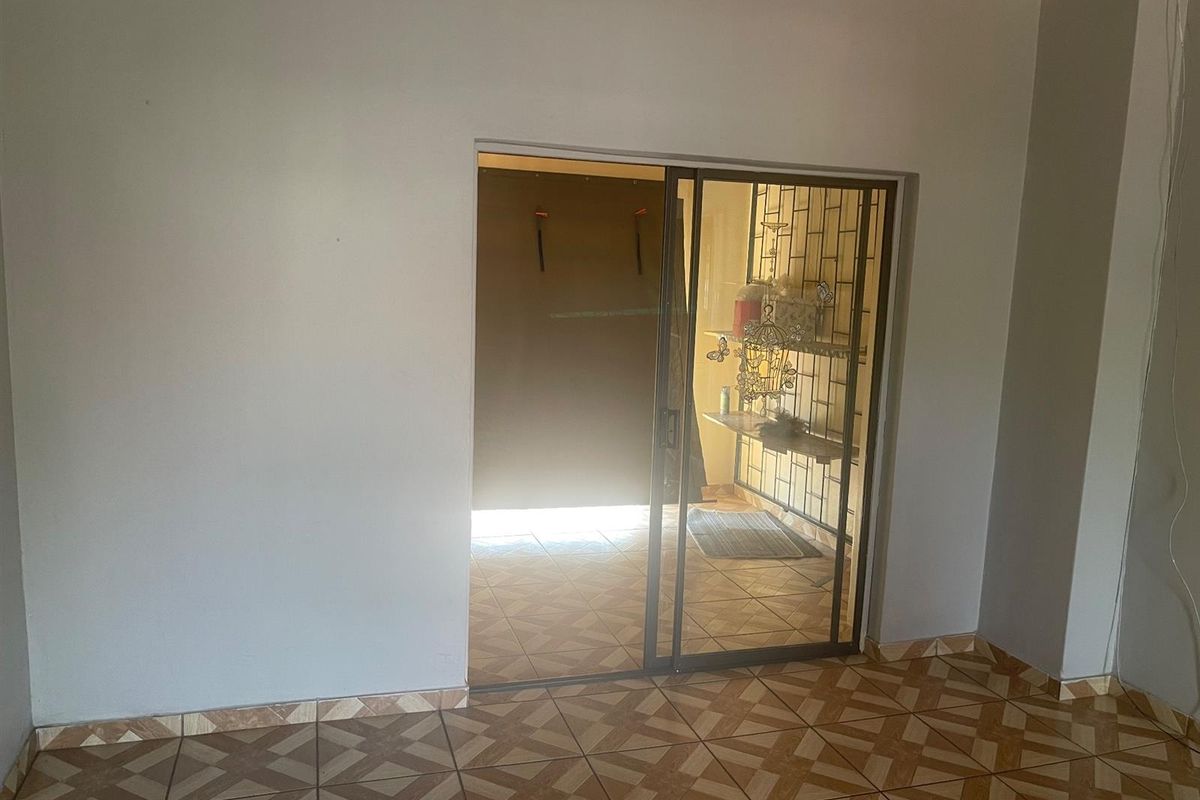 An interior view showing a tiled living area with a sliding glass door leading to an enclosed patio or secondary space.