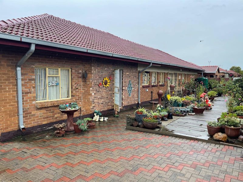 A view of the exterior front facade featuring face-brick construction, a tiled roof, and a paved driveway area.