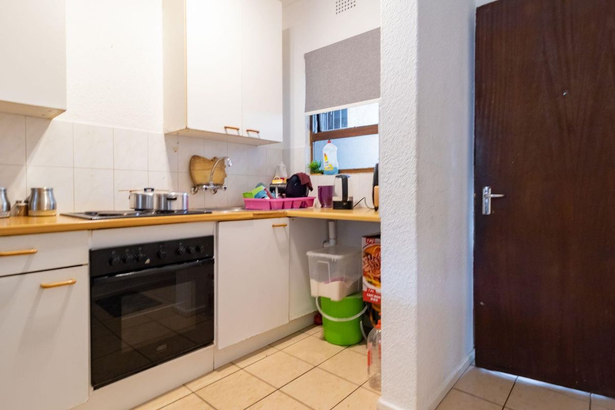 Compact kitchen featuring built-in cabinetry, an integrated electric oven and hob, tiled splashbacks, and functional laminate countertops.