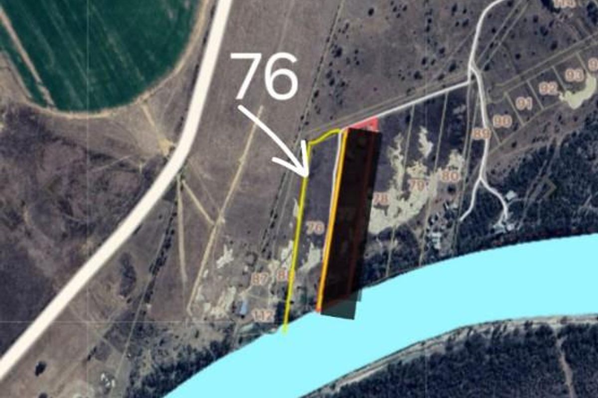 Aerial view of a vacant commercial land parcel featuring river frontage and marked boundary lines.
