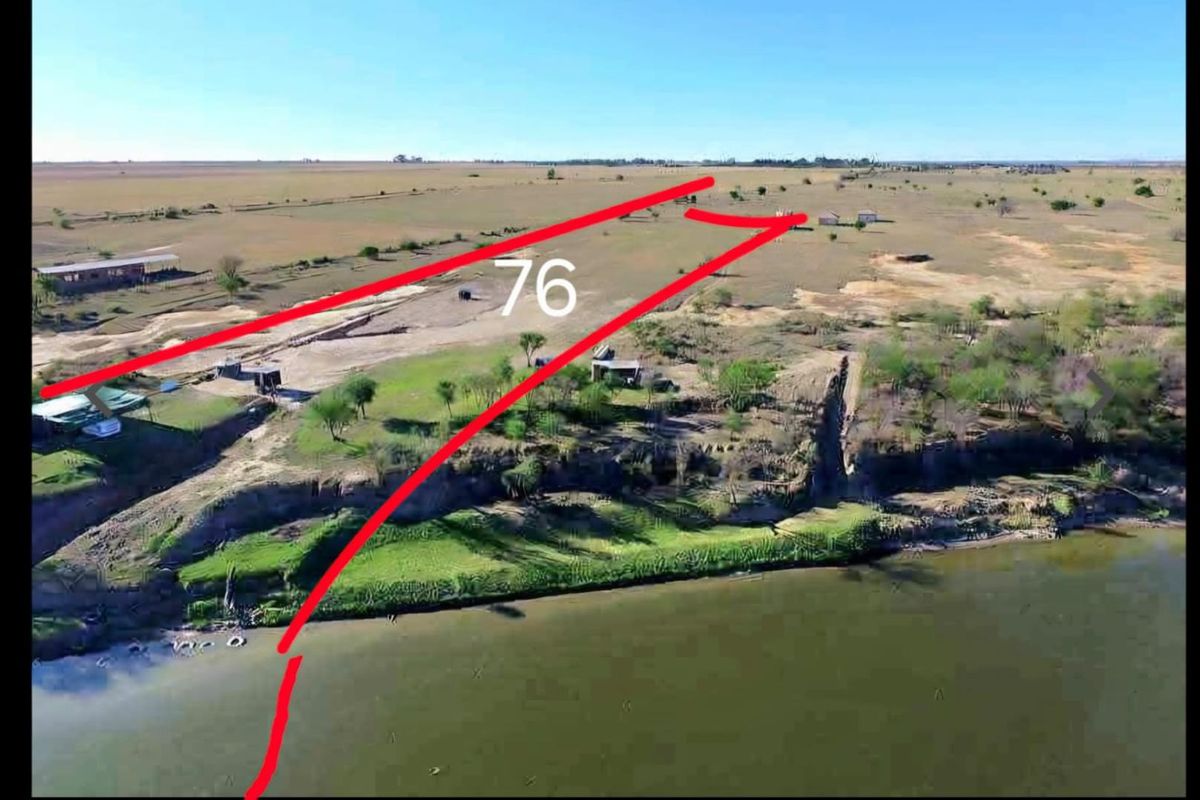 Aerial view of a large vacant commercial land parcel featuring waterfront access and open terrain.