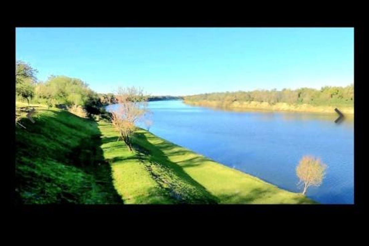 A scenic view of the river and grassy embankment, highlighting the natural landscape and waterfront potential of the commercial land.