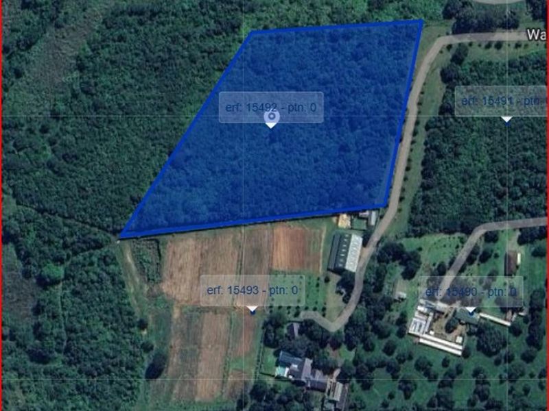 An aerial view showing the boundaries of the vacant residential land plot, highlighted in blue, surrounded by established vegetation and neighboring properties.
