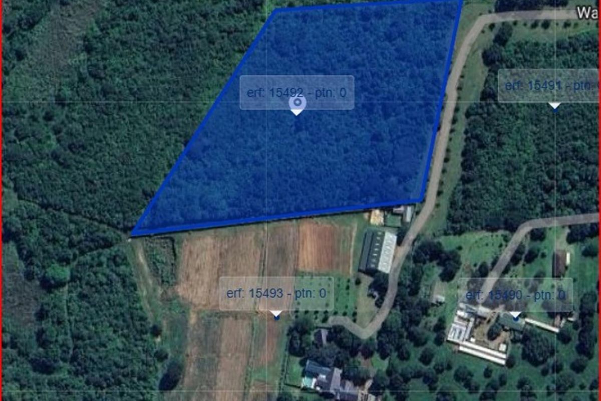 An aerial view showing the boundaries of the vacant residential land plot, highlighted in blue, surrounded by established vegetation and neighboring properties.