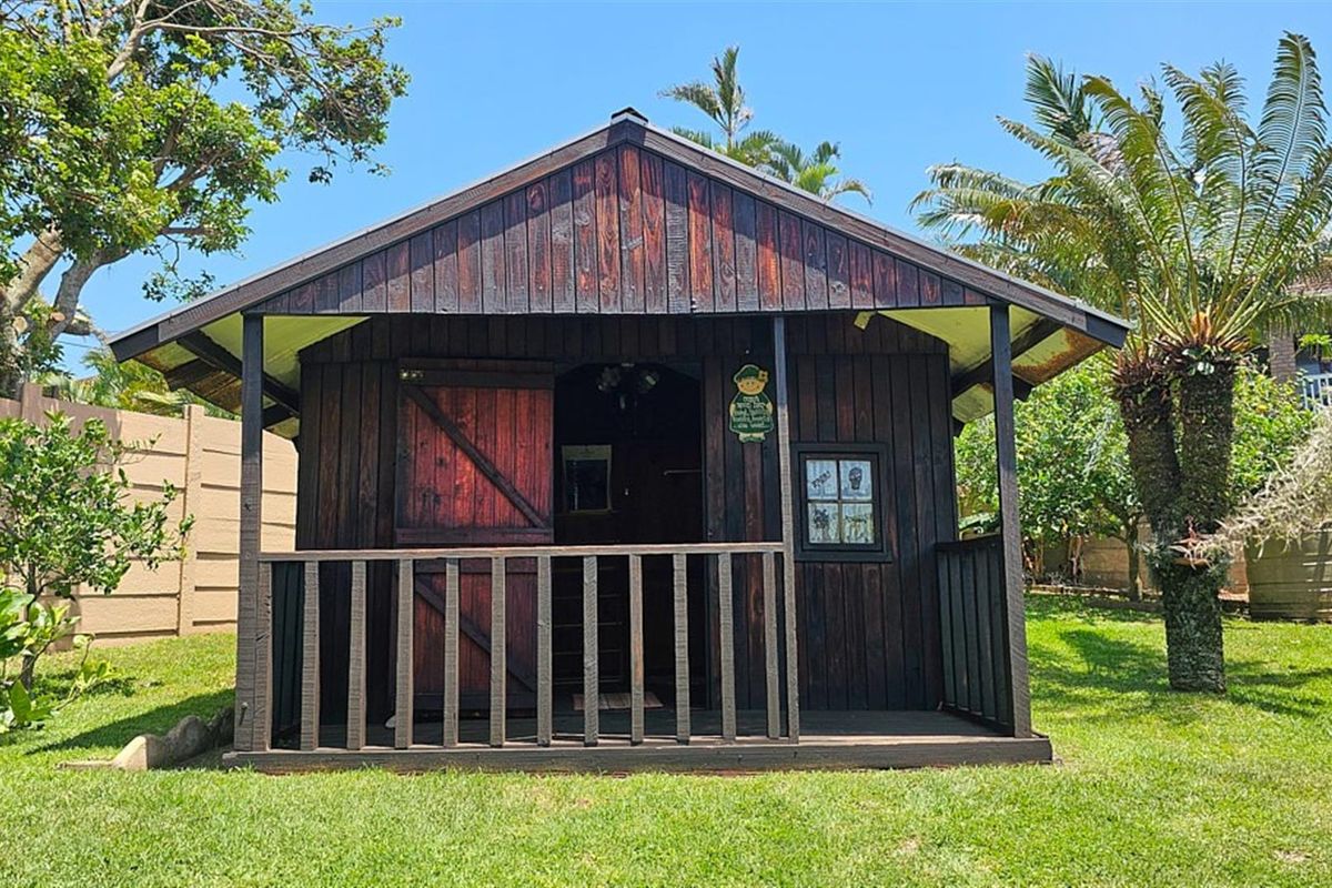 A detached timber garden cabin featuring a covered front porch, set within a landscaped garden area.