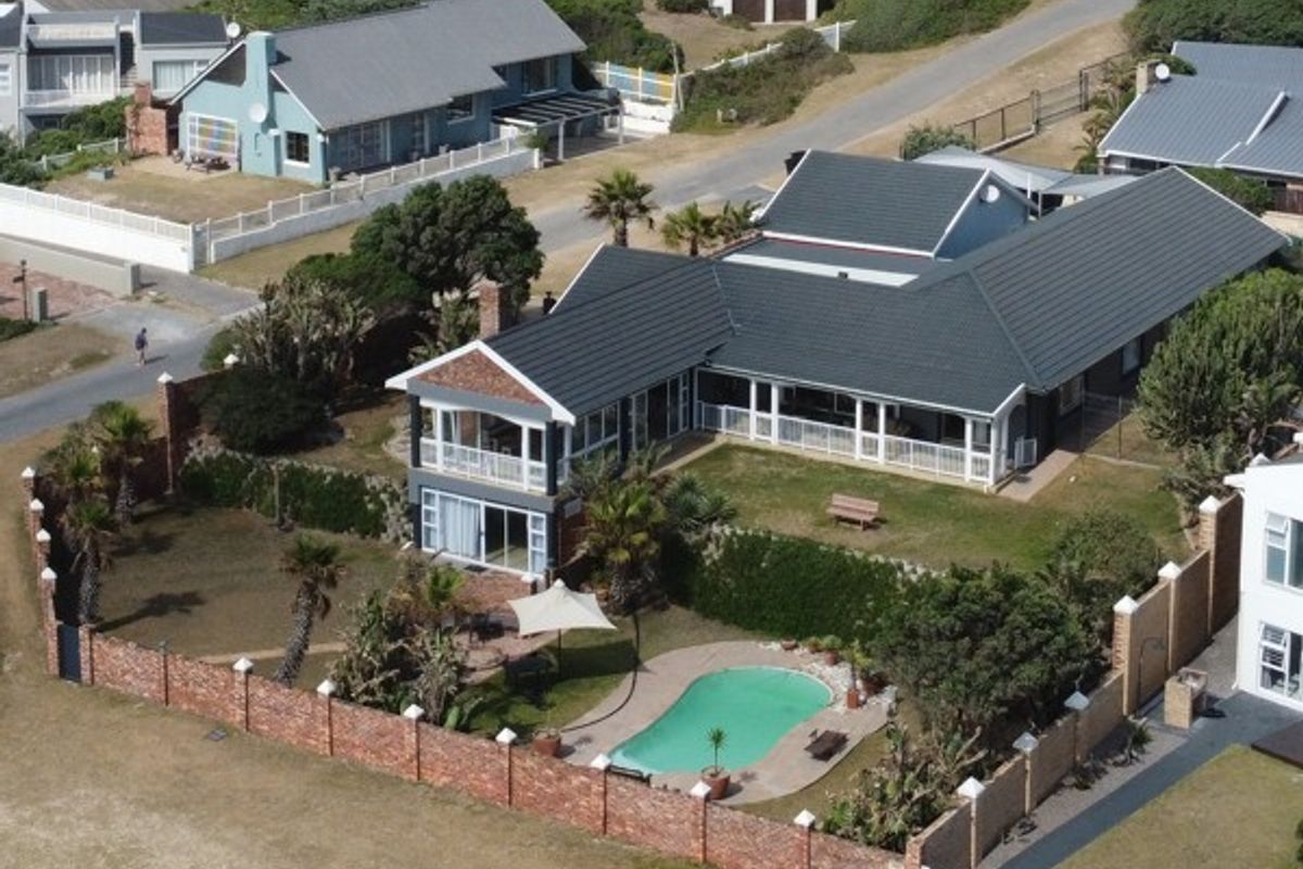 Aerial view of a residential property featuring a tiled roof, wrap-around balcony, swimming pool, and enclosed garden area with brick perimeter walling.