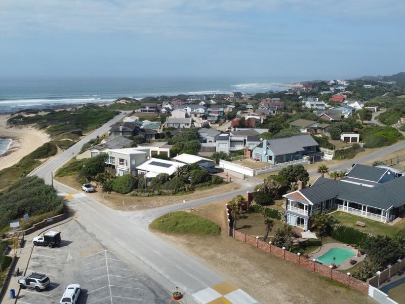 Aerial view of a coastal residential neighborhood featuring houses, paved roads, and proximity to the beach and ocean.