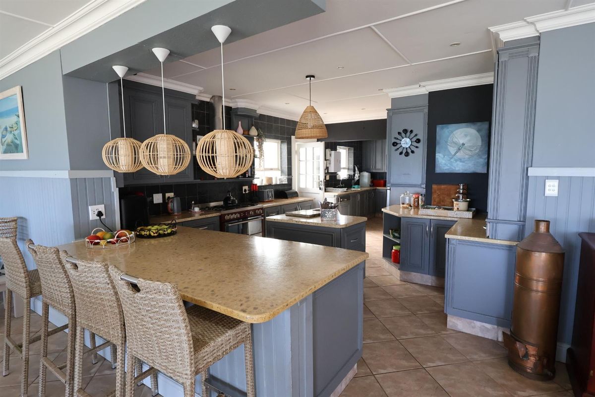 Spacious kitchen featuring a large central island, ample cabinetry, tiled flooring, and a secondary prep area, offering a functional and well-defined culinary space.