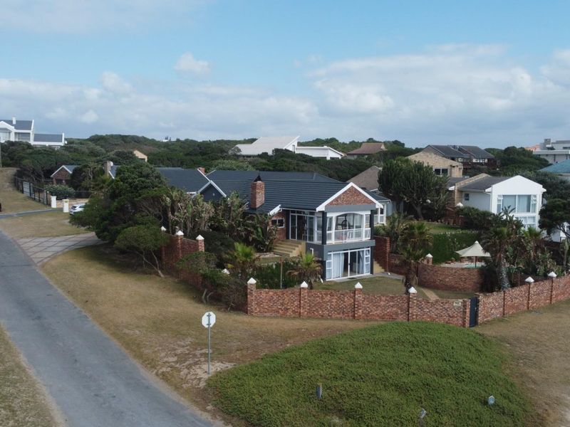 Aerial view of a coastal residential property featuring a brick perimeter wall, tiled roof, and established garden in a quiet neighborhood setting.