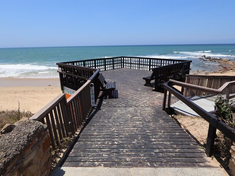 An elevated wooden viewing deck overlooking the beach, featuring timber railings and direct access to the coastline.