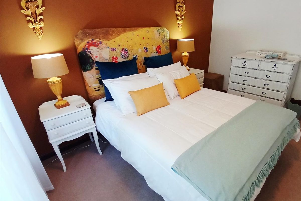 A well-maintained bedroom featuring a warm-toned accent wall and neutral carpeting.