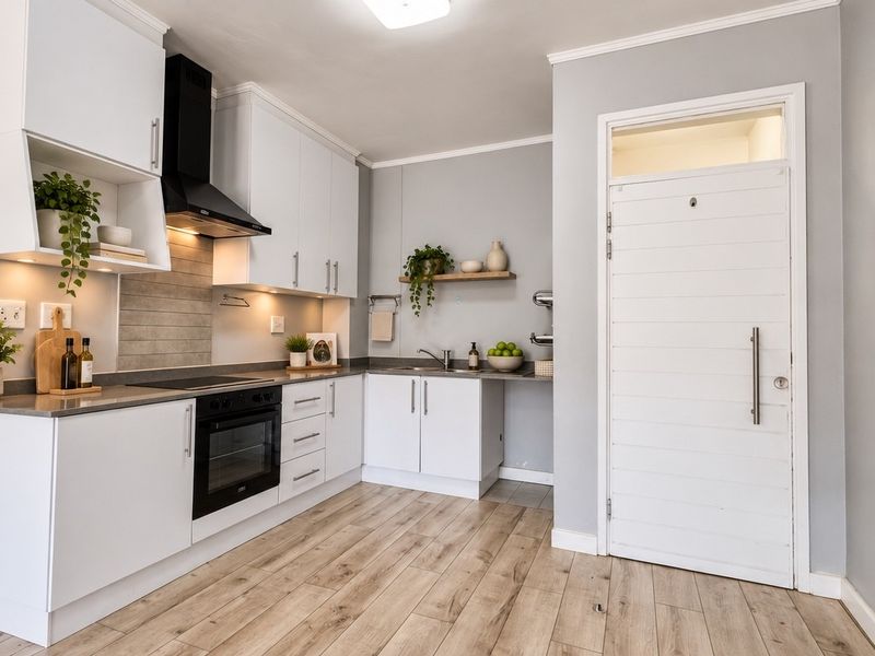 Modern kitchen featuring white cabinetry, integrated appliances, wood-look laminate flooring, and a clean, contemporary aesthetic with a functional layout.