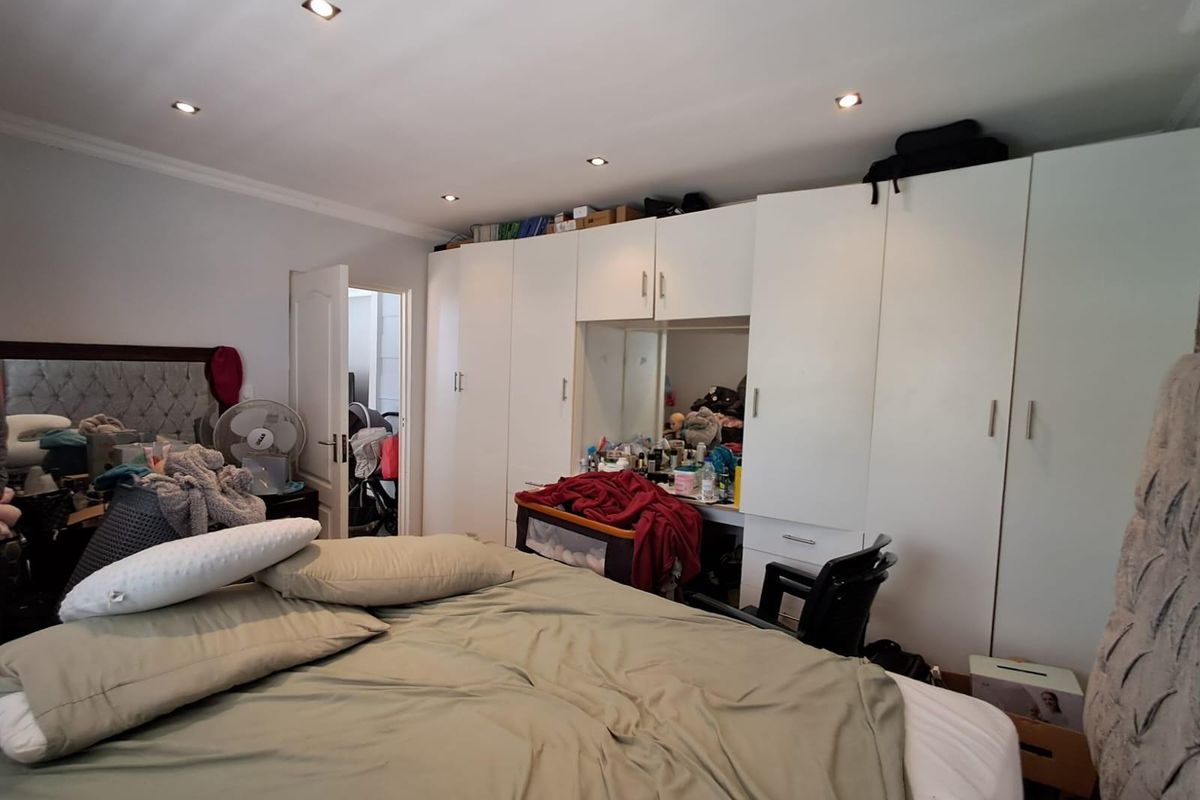 A bedroom featuring extensive built-in white cabinetry with integrated vanity and recessed ceiling downlights.