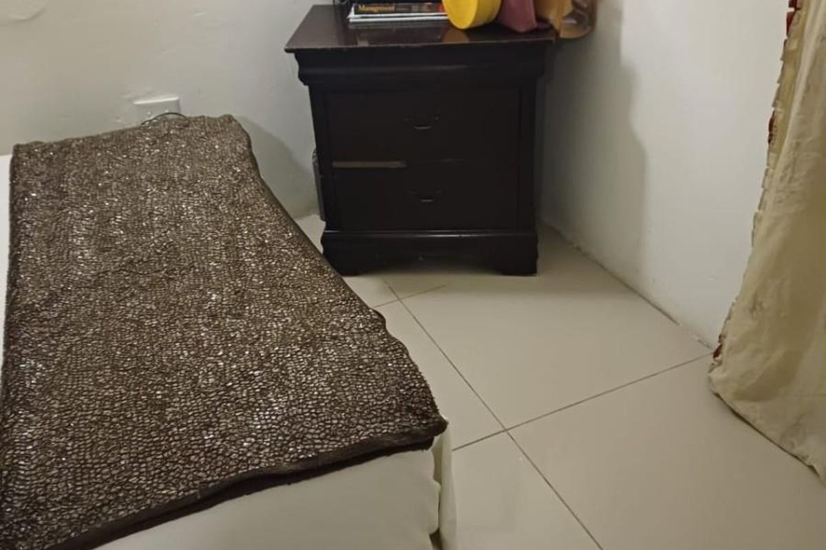 A bedroom featuring tiled flooring and a neutral wall finish, providing a functional space for rest.