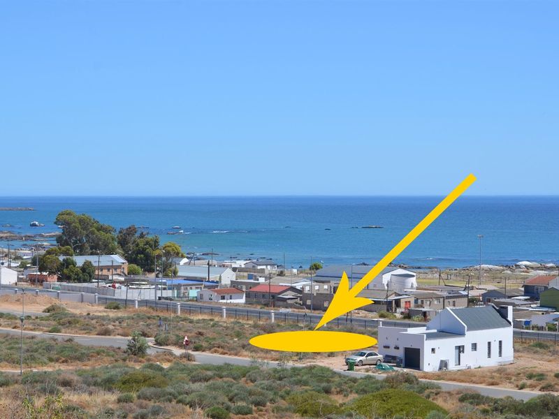 An elevated aerial view of a vacant residential plot located in a coastal neighborhood, featuring clear ocean views and proximity to existing infrastructure.