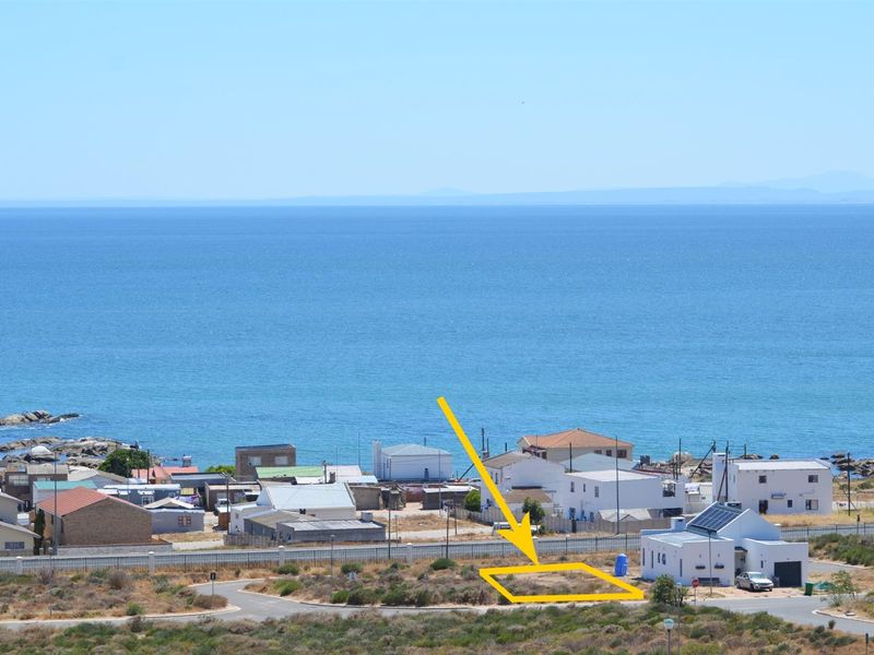 An elevated aerial view of a vacant residential plot situated in a coastal neighborhood, featuring prominent ocean views and proximity to existing residential infrastructure.
