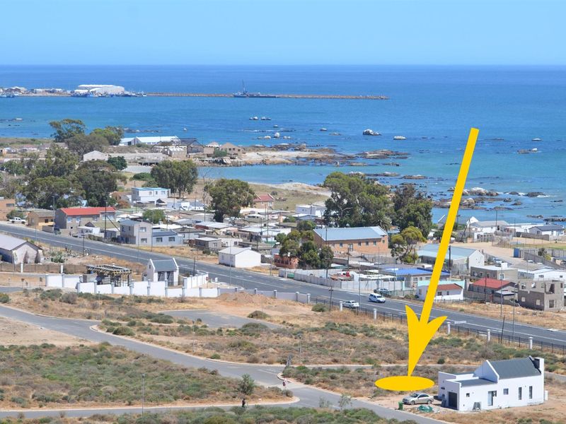 Aerial view of a residential plot located in a coastal area, featuring proximity to the ocean and local infrastructure.