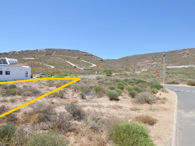A vacant residential plot of land situated in a coastal estate, featuring natural vegetation and proximity to established infrastructure and paved roads.