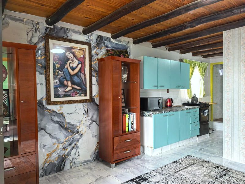 Kitchen area featuring exposed timber ceiling beams, tiled flooring, and built-in cabinetry with a freestanding stove.