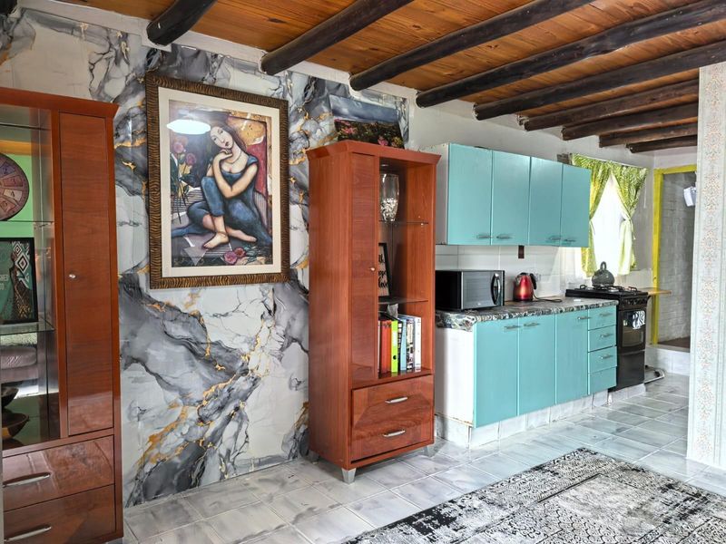 Kitchen area featuring exposed timber ceiling beams, marble-effect wall accents, and blue cabinetry with a freestanding stove.