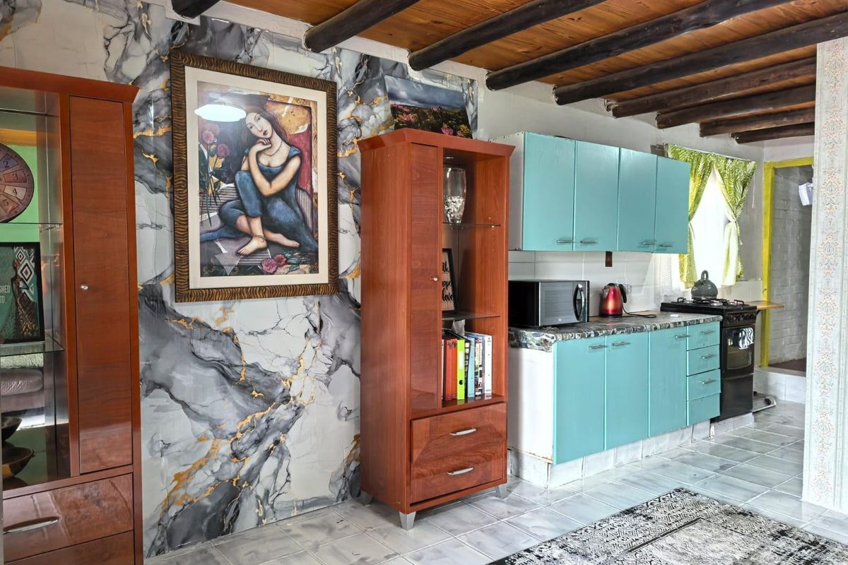 Kitchen area featuring exposed timber ceiling beams, marble-effect wall accents, and blue cabinetry with a freestanding stove.