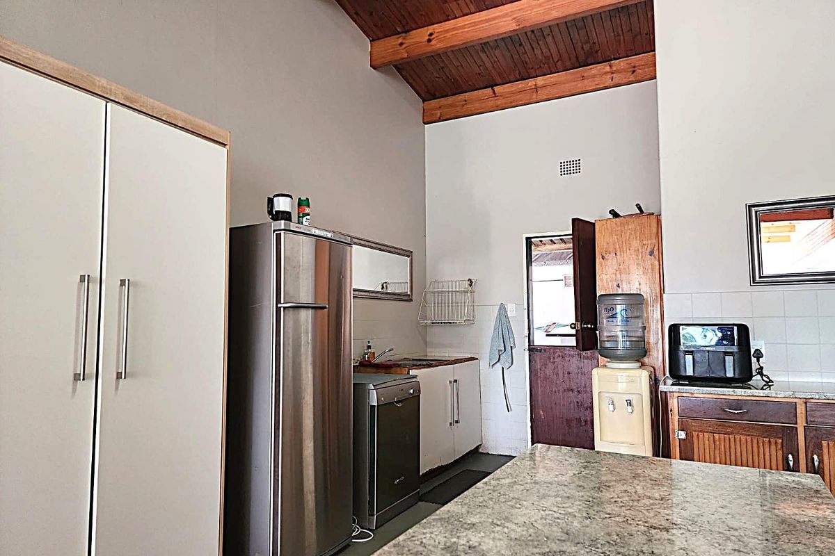 A functional kitchen area featuring granite countertops, built-in cabinetry, and a high vaulted timber ceiling, providing a rustic yet practical workspace.