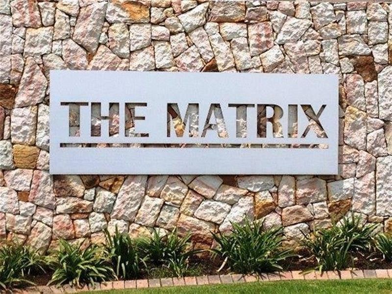 A stone-clad feature wall displaying the property name, The Matrix, at the entrance of the apartment complex.
