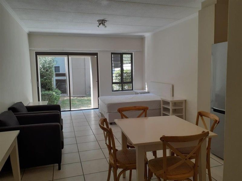 Open-plan living area featuring tiled flooring and a sliding glass door providing access to the exterior garden area.