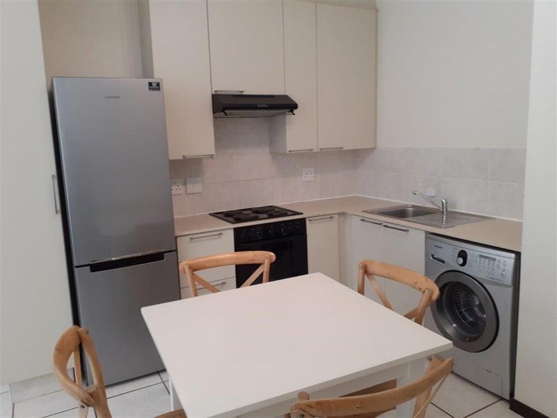 Compact kitchen featuring built-in cabinetry, laminate countertops, a stainless steel sink, built-in oven with gas hob, and an extractor fan.