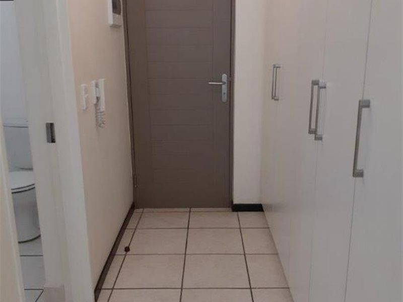 A clean, functional hallway featuring neutral tiled flooring and extensive built-in storage cupboards with modern hardware.