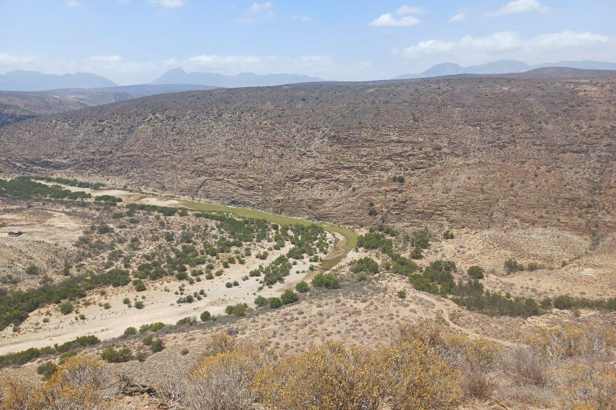 A scenic elevated view of the expansive arid landscape, featuring a winding riverbed through the valley and distant mountain ranges.