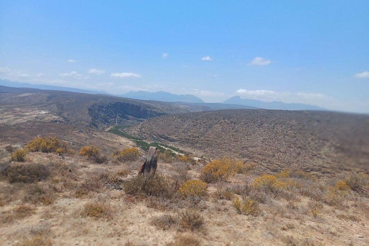 A panoramic landscape view showcasing the expansive natural terrain, rolling hills, and distant mountain ranges characteristic of the farm property.
