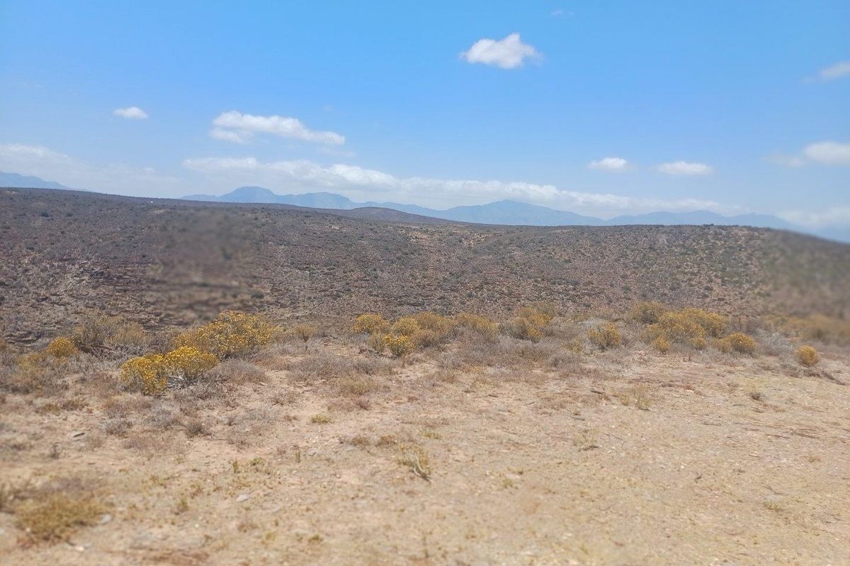 Expansive landscape view overlooking arid terrain and distant mountain ranges, showcasing the natural setting of the farm property.