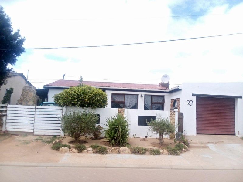 Front elevation of a single-story residential property featuring a garage, stone accents, and a corrugated metal roof.
