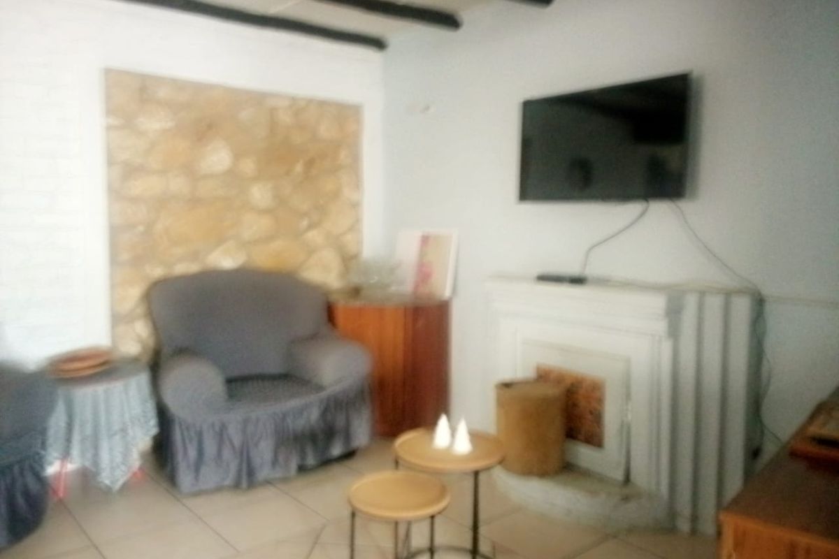 Living room featuring a stone accent wall, exposed ceiling beams, tiled flooring, and a fireplace.