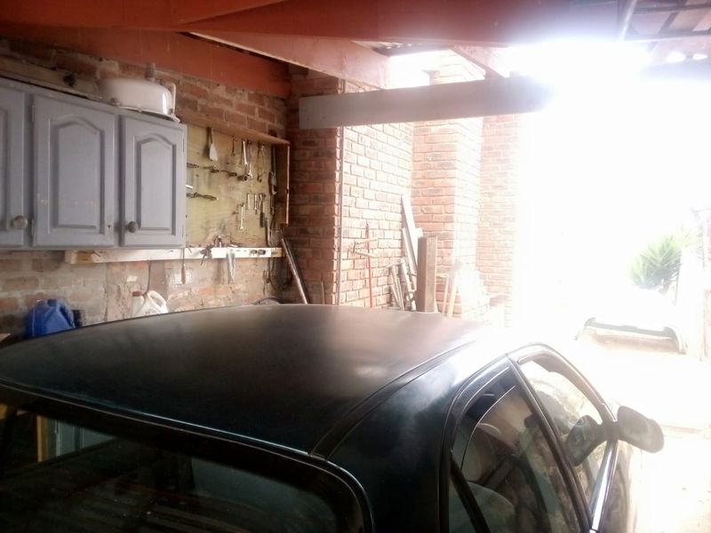 A functional garage space featuring exposed brick walls, timber roof beams, and built-in wall-mounted storage cabinetry.
