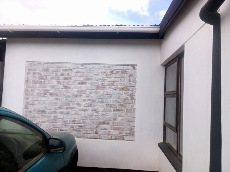 Exterior view of the property facade featuring a decorative brick accent wall and aluminium window frames.