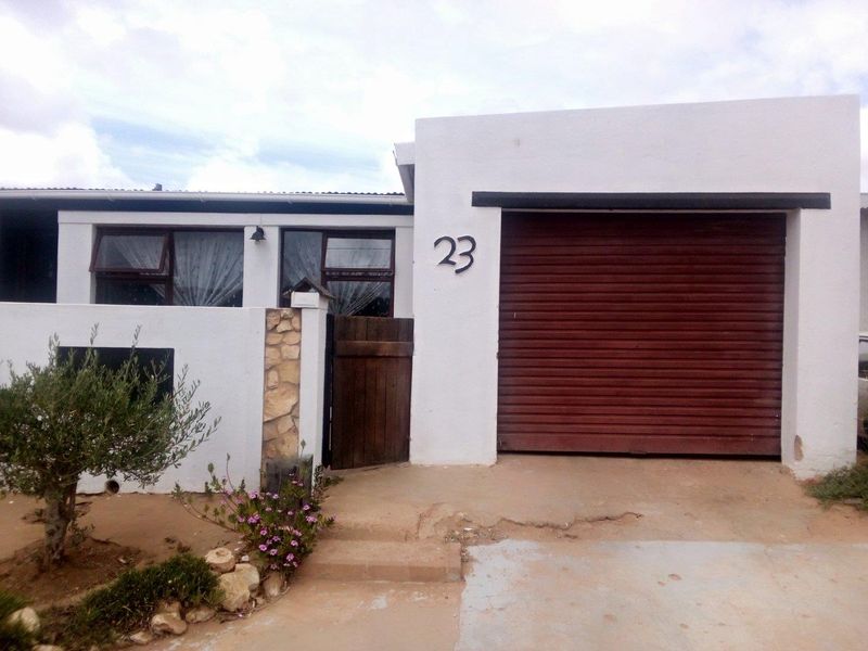 Front facade of the property featuring a single garage, stone accent wall, and timber pedestrian gate entrance.
