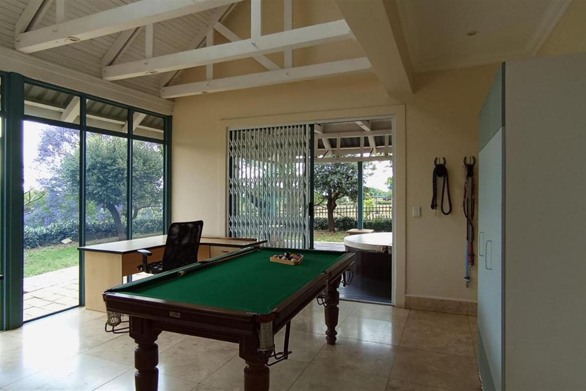 Spacious living area featuring vaulted ceilings, large glass windows, and sliding doors leading to an outdoor patio area.