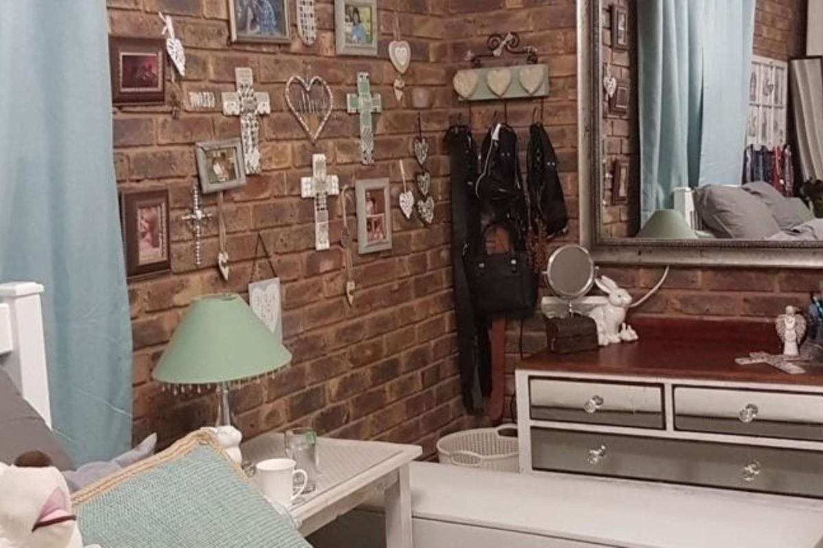 A bedroom featuring a rustic exposed brick feature wall and a large wall-mounted mirror.