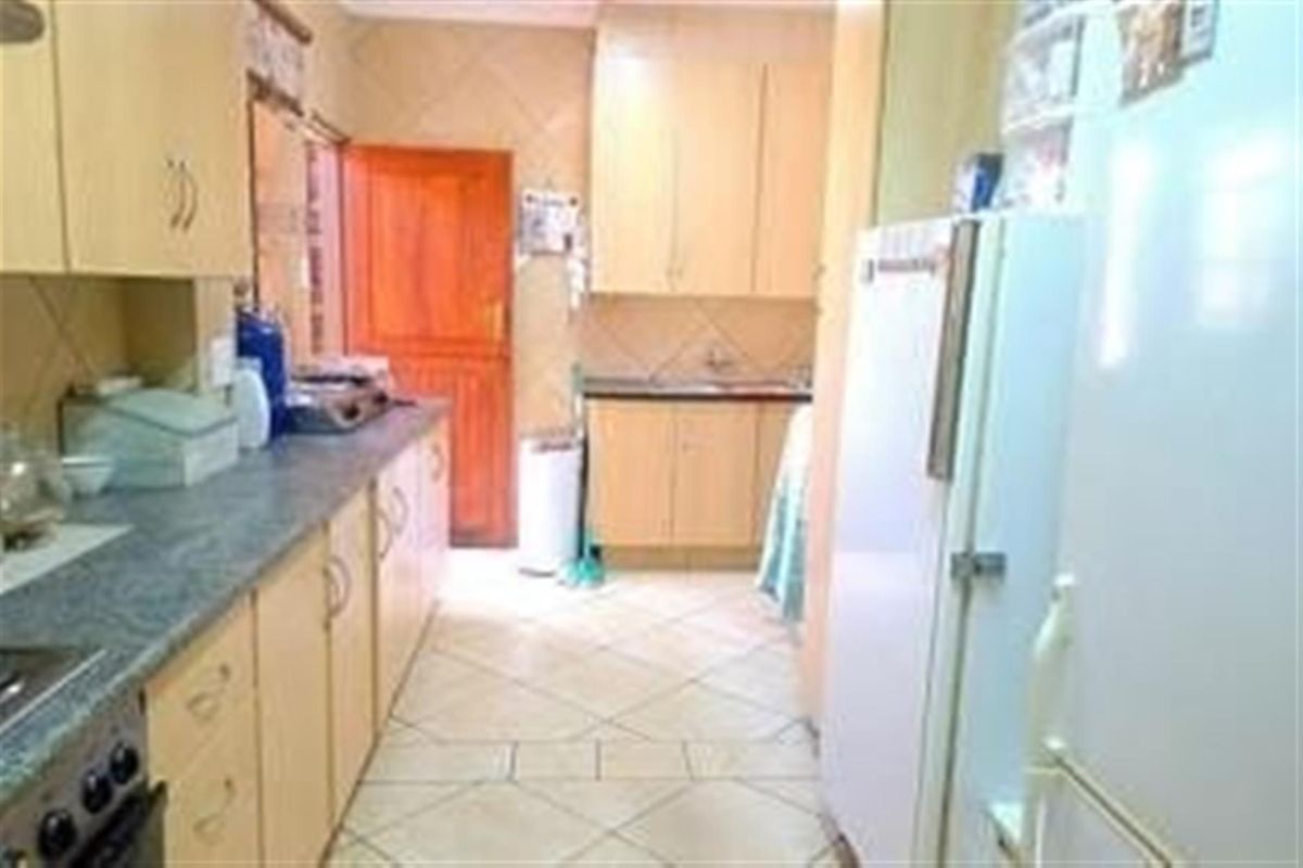 A functional kitchen featuring light-toned cabinetry, granite-look countertops, tiled flooring, and a direct access door to the exterior.