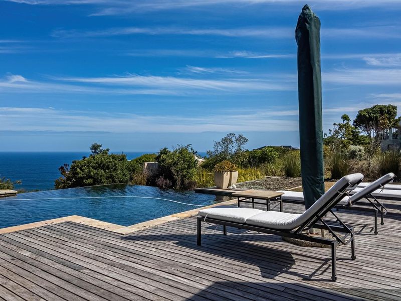 An outdoor pool area featuring an infinity edge swimming pool and timber decking with expansive ocean views.