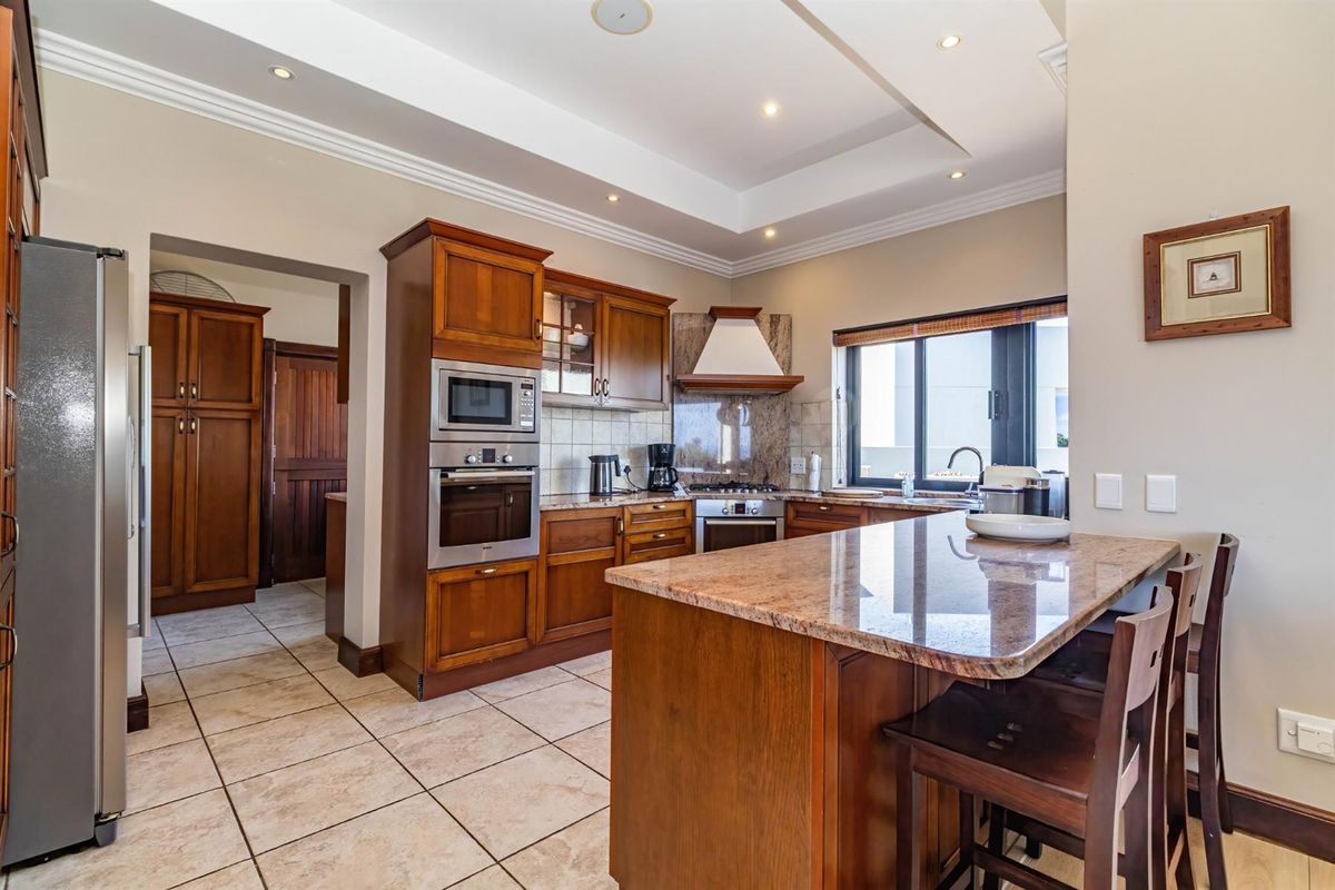 A well-appointed kitchen featuring wooden cabinetry, granite countertops, built-in appliances, and a central island with breakfast bar seating.