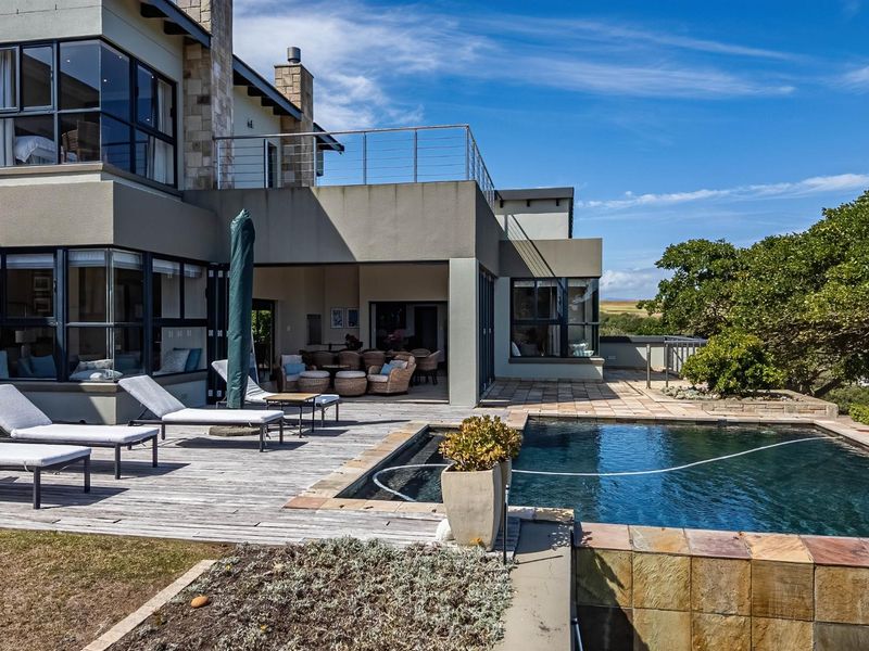Spacious outdoor entertainment area featuring a swimming pool, timber decking, covered patio, and an upper-level balcony with modern architectural finishes.
