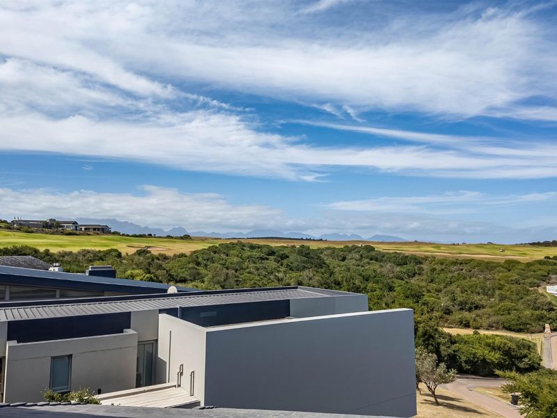 Elevated view overlooking a golf course and natural landscape, featuring modern architectural roof lines and clean exterior finishes.